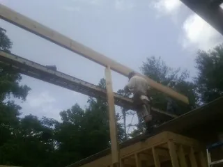 Carpenter setting a ridge beam over a new addition frame — Ice Dam Removal by Roofing Brothers in Alvin