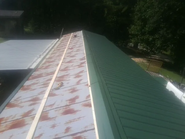 Old rusted panels beside newly installed green metal roofing — Wind Damage Roof Repair by Roofing Brothers in Alvin