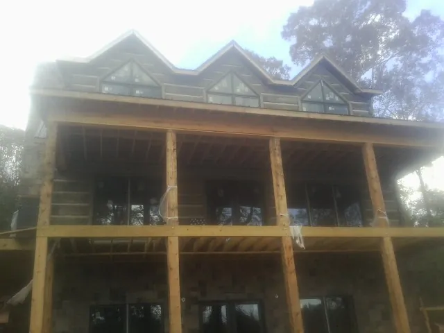 Dormers and porch framing on a large log home under construction — Roof Coating work by our crew in Alvin