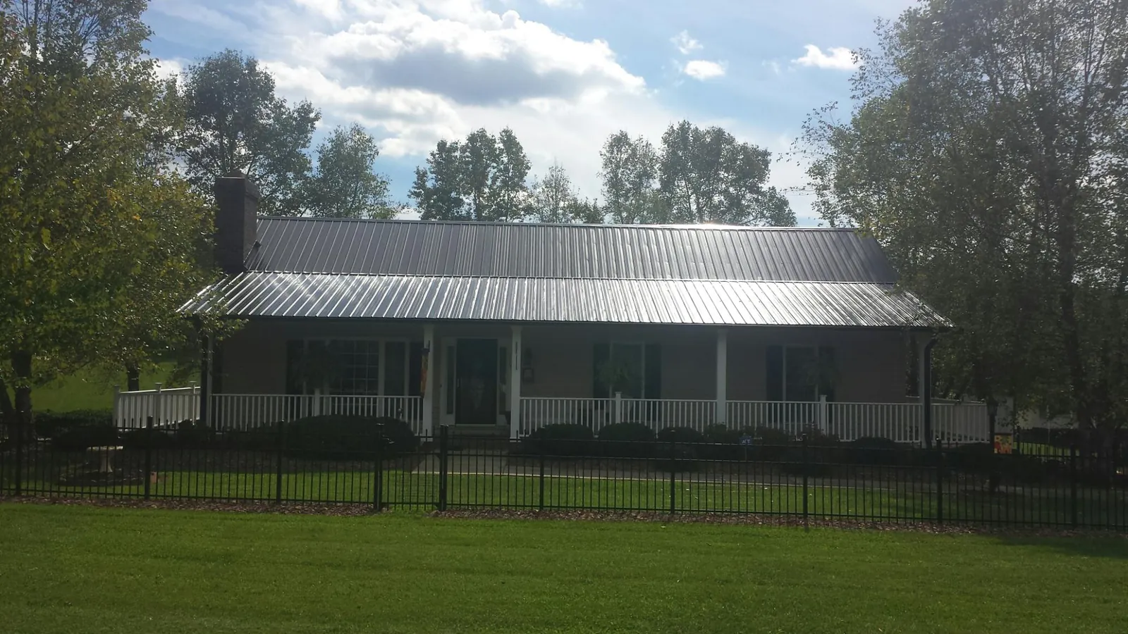 Gray metal roof on a brick ranch with a full width front porch — Gutter Guard Installation work by our crew in Alvin