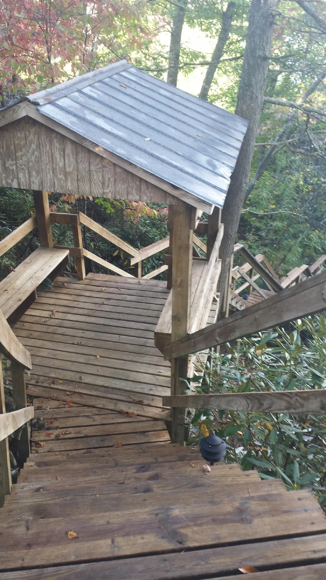 Metal roofed shelter over wooden steps on a wooded walkway — Skylight Repair & Installation work by our crew in Alvin
