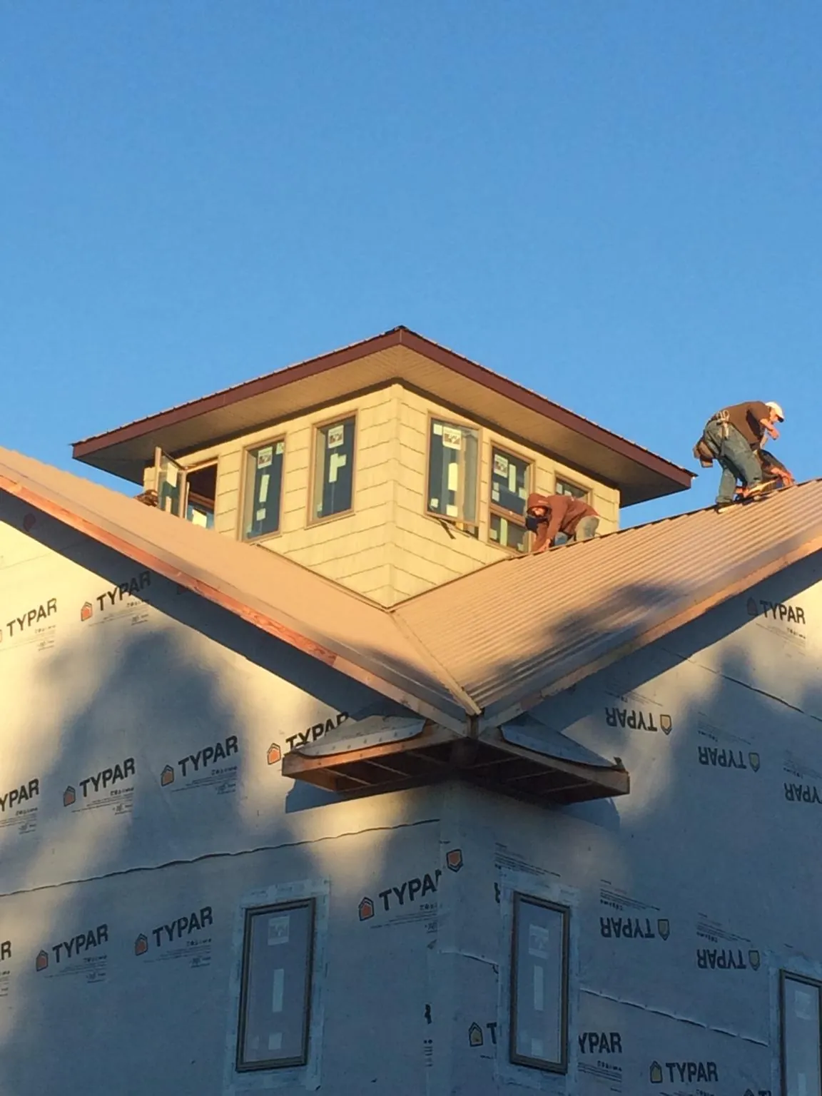 Roofers working around a rooftop cupola on a new metal roof at sunset — Roof Waterproofing in Alvin by Roofing Brothers